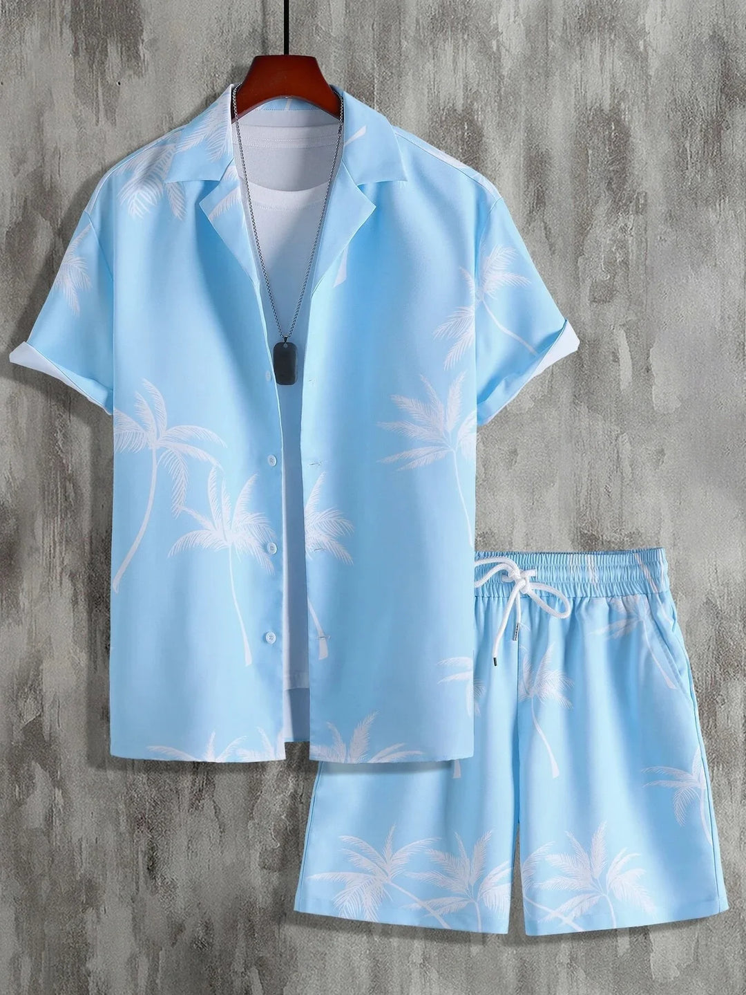 Light blue tropical print short sleeve shirt and shorts set with white drawstring on gray background