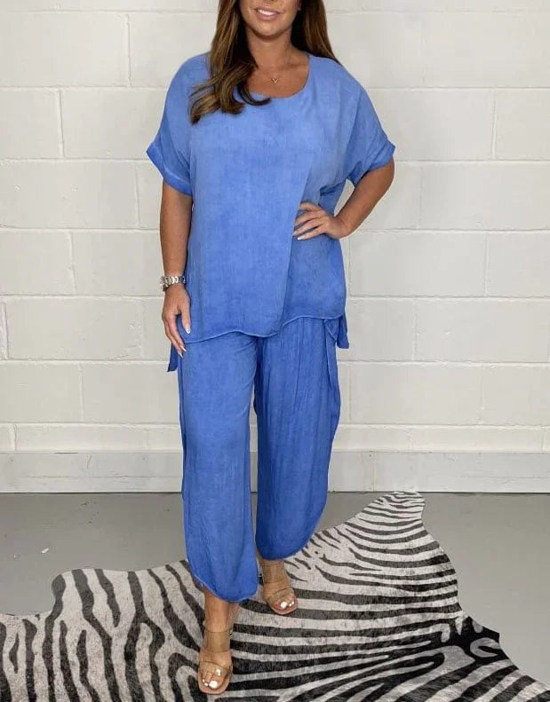 Woman wearing a loose blue short-sleeve top and wide-leg pants standing on zebra print rug