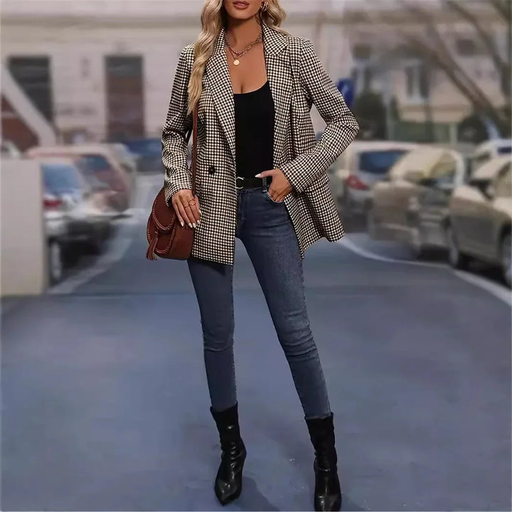 Woman wearing houndstooth blazer, black top, skinny jeans, and black ankle boots standing on city street