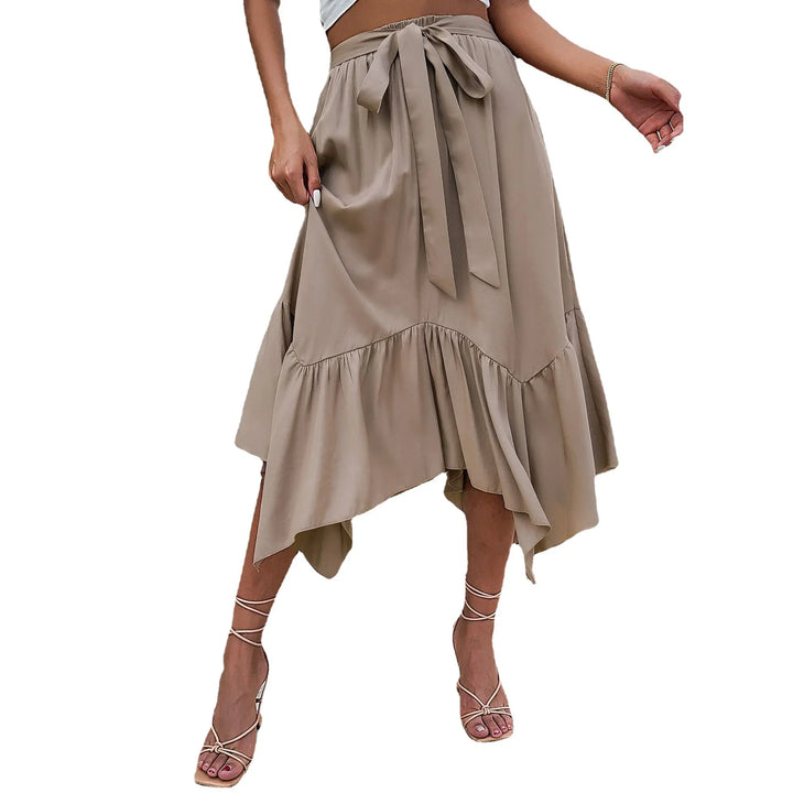 Woman wearing a beige high-waisted midi skirt with asymmetrical hem and tied waist bow