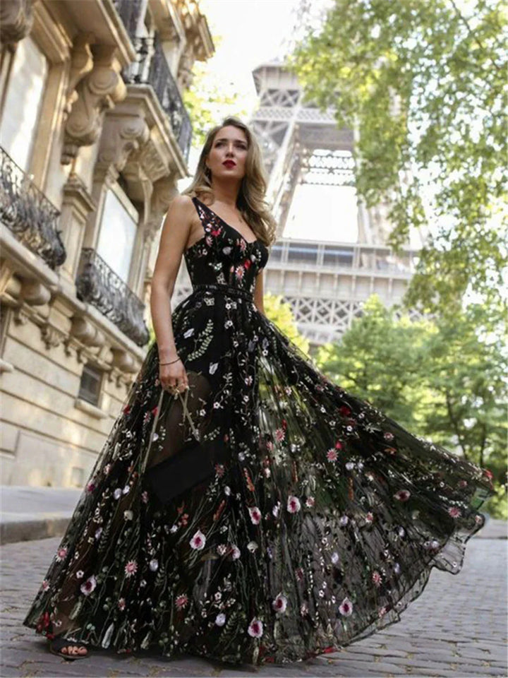 Woman wearing a black floral maxi dress with sheer fabric in front of the Eiffel Tower in Paris