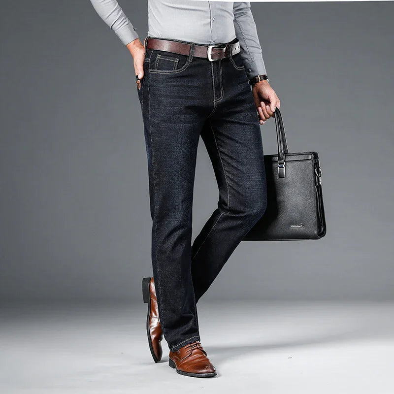 Man wearing dark blue jeans, brown leather belt, brown dress shoes, holding black leather briefcase