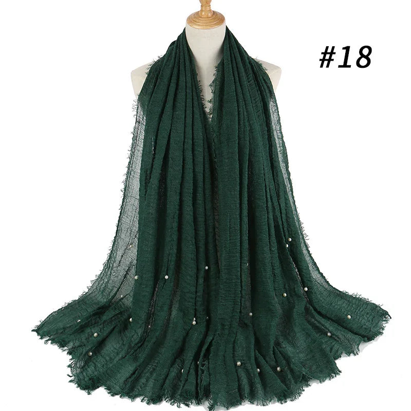 Dark green textured scarf with small pearl accents displayed on dress form