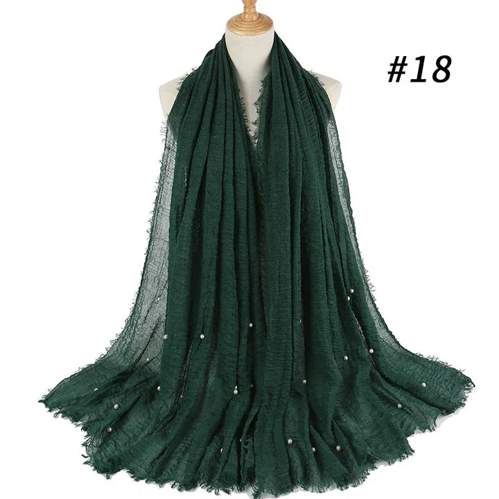 Dark green textured scarf with small pearl accents displayed on dress form