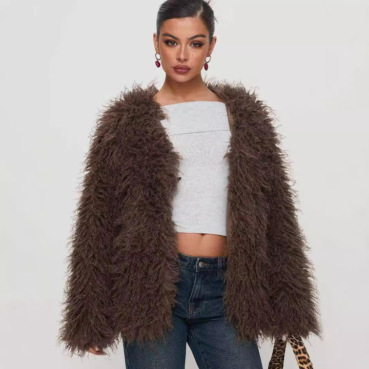 Woman wearing a brown fluffy faux fur jacket, white crop top, blue jeans, and red drop earrings
