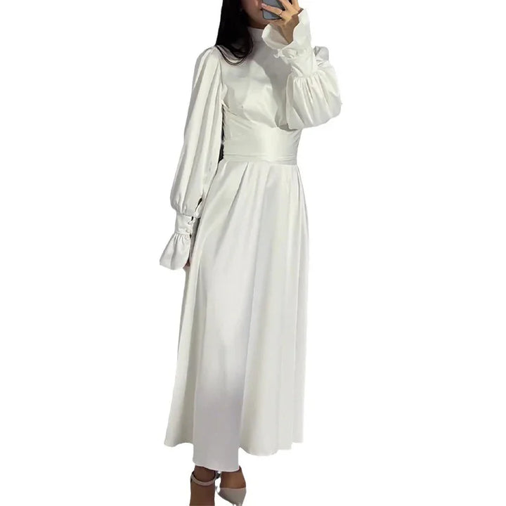 Woman wearing long white puff sleeve maxi dress with high neckline and fitted waist