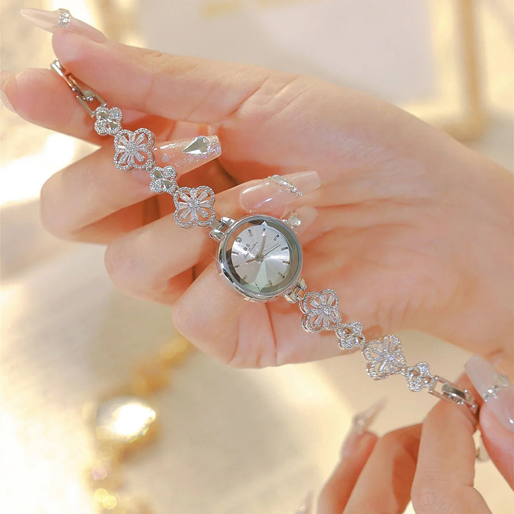 Close-up of hands holding silver floral bracelet watch with decorative dial and clear nail art