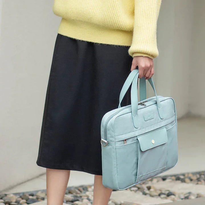 Person holding pastel blue laptop bag with front pocket, wearing yellow sweater and black skirt