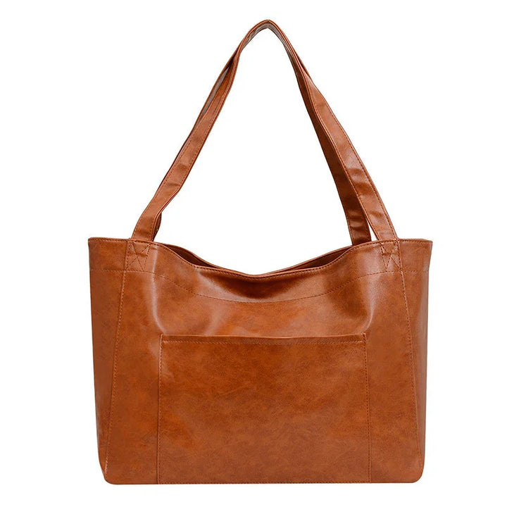 Brown leather tote handbag with front pocket and double handles on white background