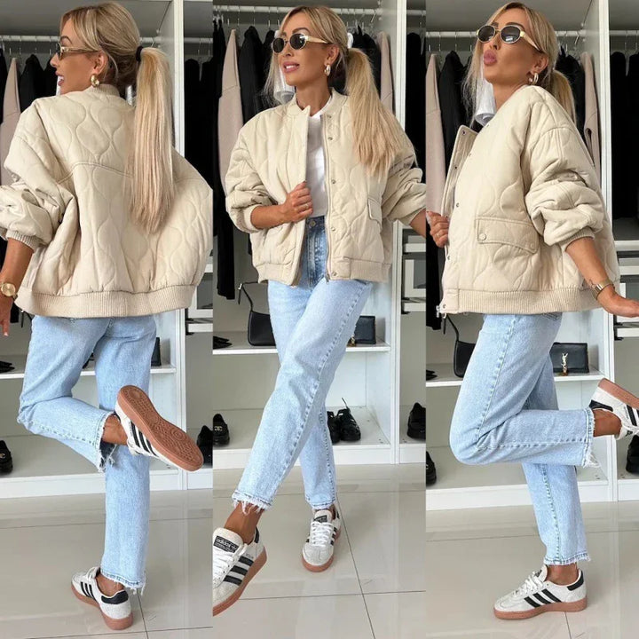 Woman wearing beige quilted jacket, white t-shirt, light blue jeans, and Adidas sneakers in closet setting