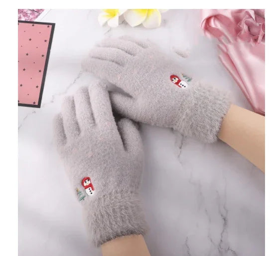 Soft gray winter gloves with cute snowman and red scarf embroidery on white marble surface