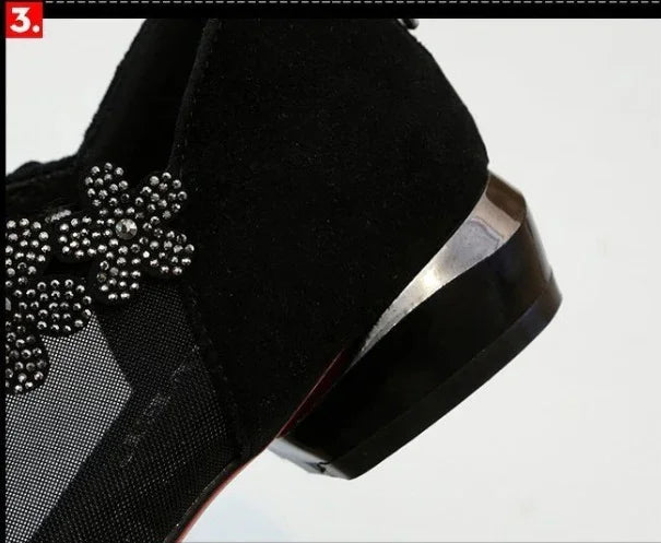 Close-up of black suede shoe heel with silver metal accent and decorative studded flower design