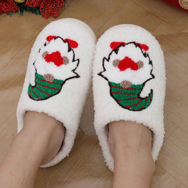 White fuzzy Christmas slippers with cute Santa Claus design worn on feet over wooden floor