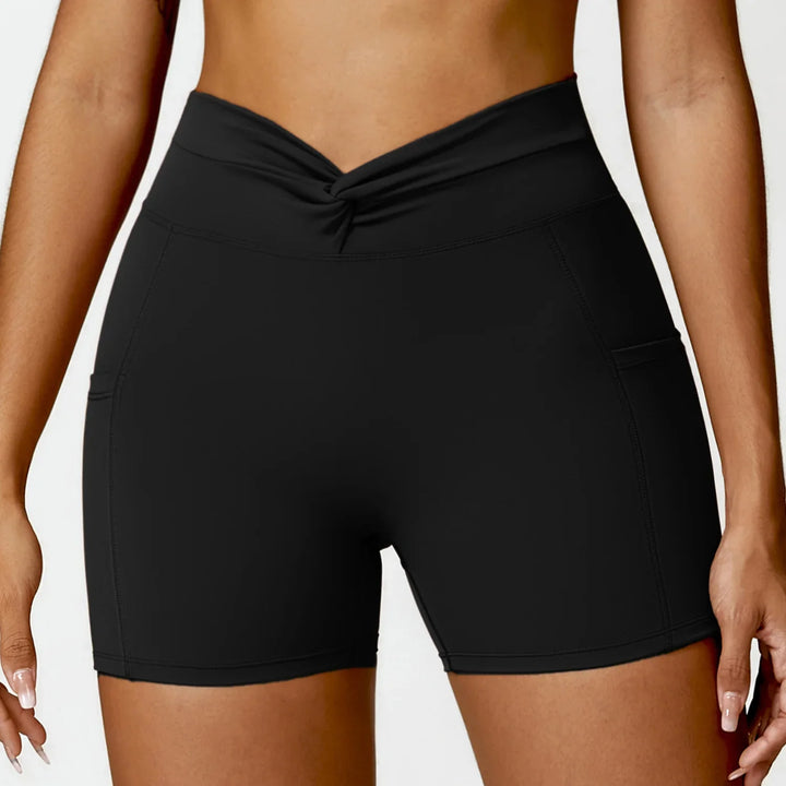 Close-up of woman wearing black high-waisted athletic shorts with twist waistband and side pockets
