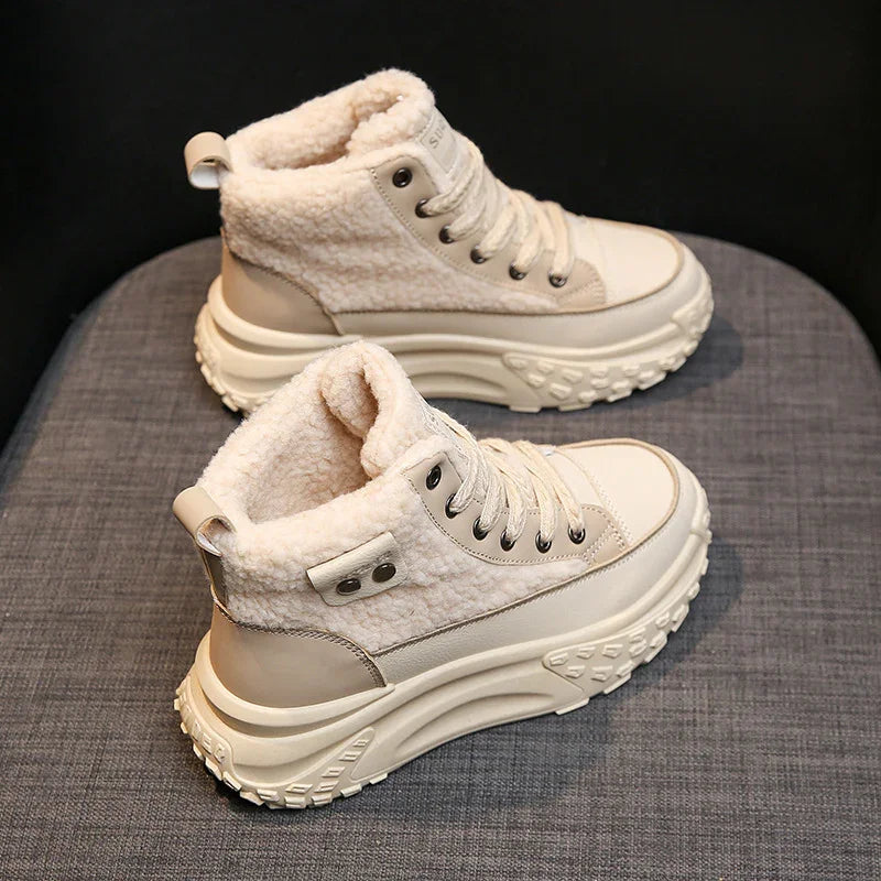 Beige high-top sneakers with thick treaded soles and plush fleece lining on gray surface