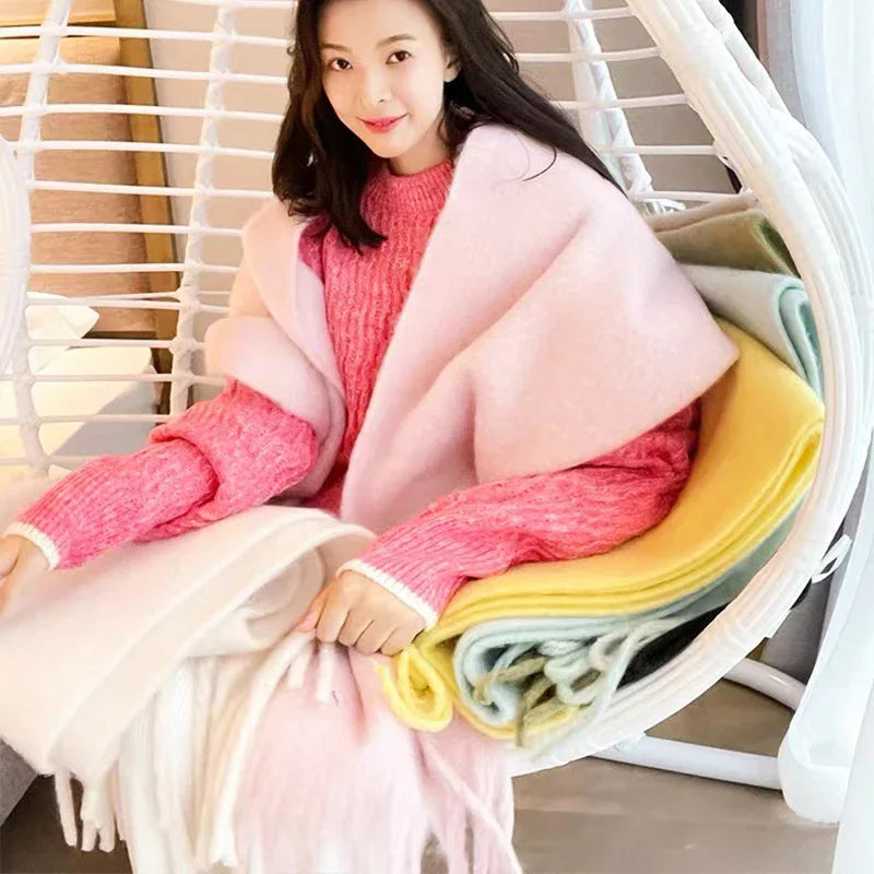 Smiling woman in pink sweater and shawl sitting on white hanging egg chair with colorful blankets
