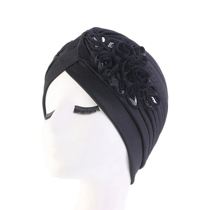 Black turban hat with floral appliqué and sequin detailing on white mannequin head