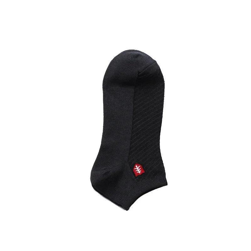 black ankle sock with textured pattern and small red logo on white background