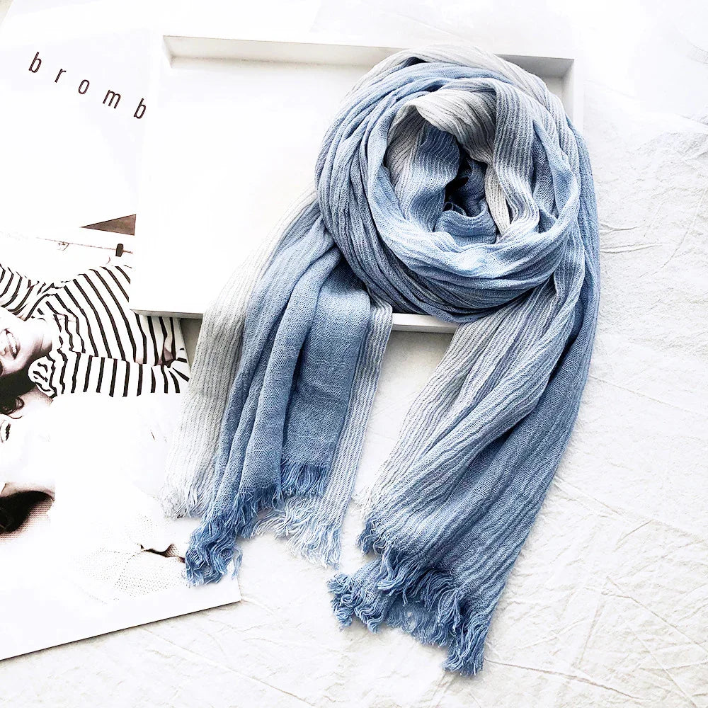 Light blue and white striped soft scarf with fringed edges on white textured surface