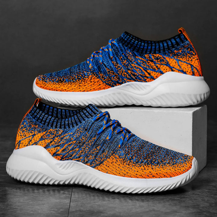 Pair of blue and orange knitted athletic sneakers with white soles on gray surface
