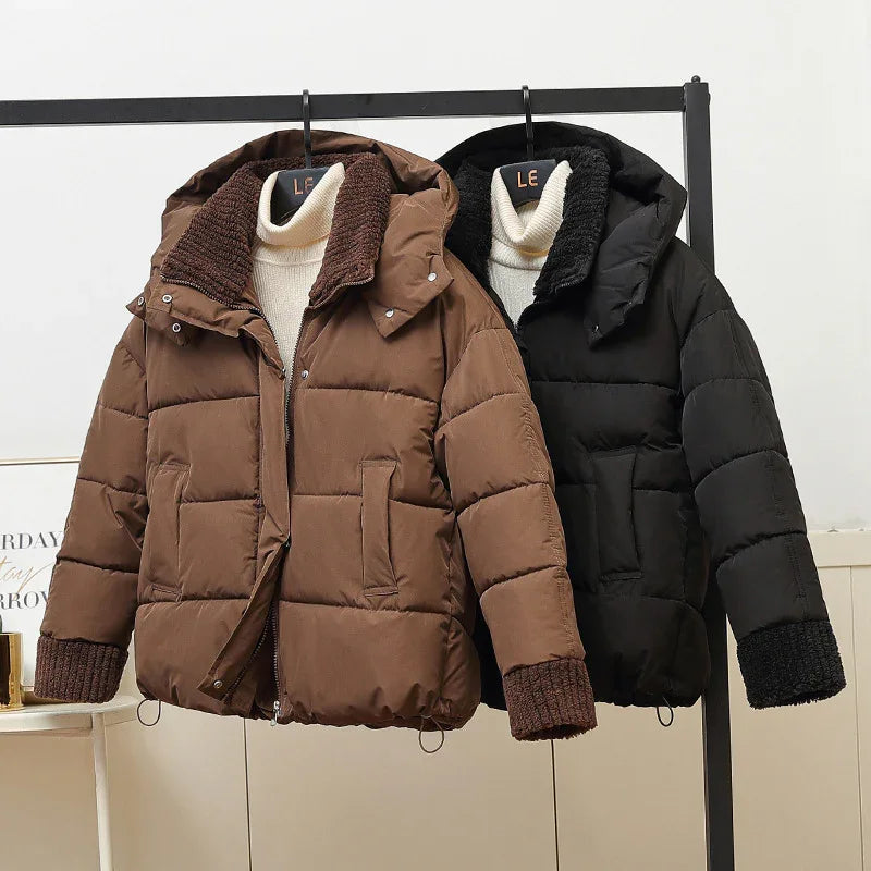 Brown and black padded winter jackets with knit cuffs and collars hanging on a rack with cream turtleneck sweaters