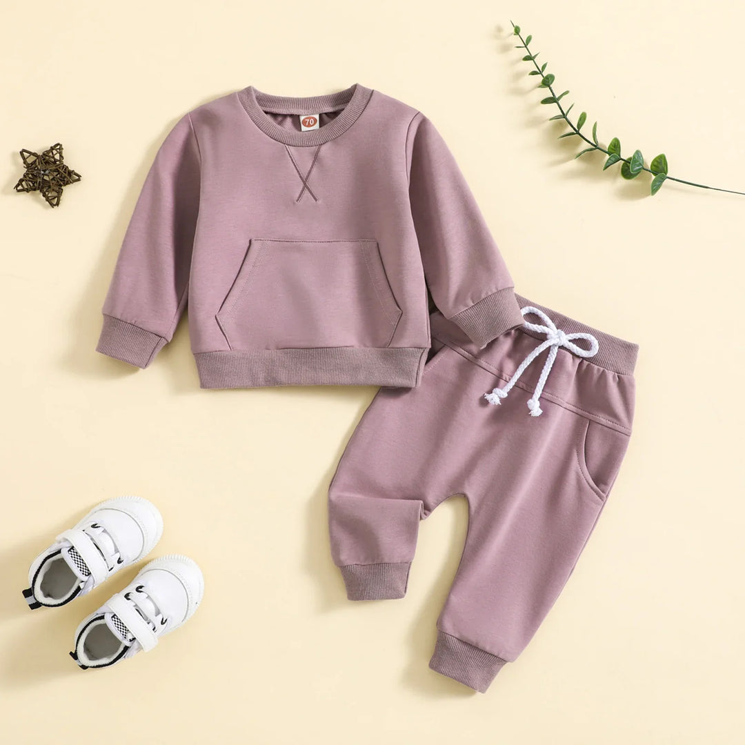 Purple toddler sweatshirt and pants set with white drawstring, white kids sneakers on beige background