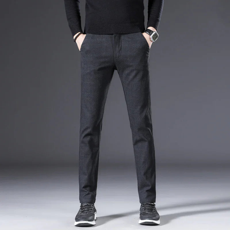 Men's slim-fit dark gray casual pants paired with black sneakers and a black sweater