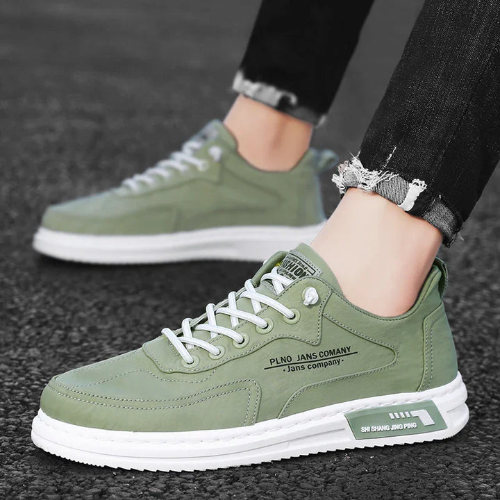 Casual green sneakers with white soles and laces worn with black distressed jeans on asphalt