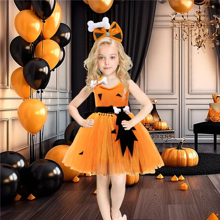 Young girl in orange Halloween pumpkin dress with black and white bone accessories at decorated party room