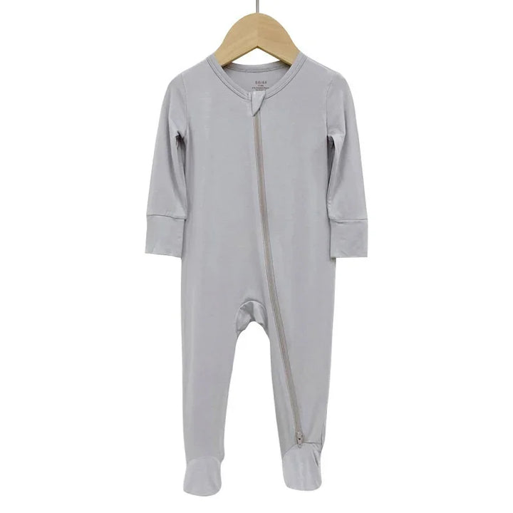 Light gray baby onesie with front diagonal zipper and footed legs on wooden hanger