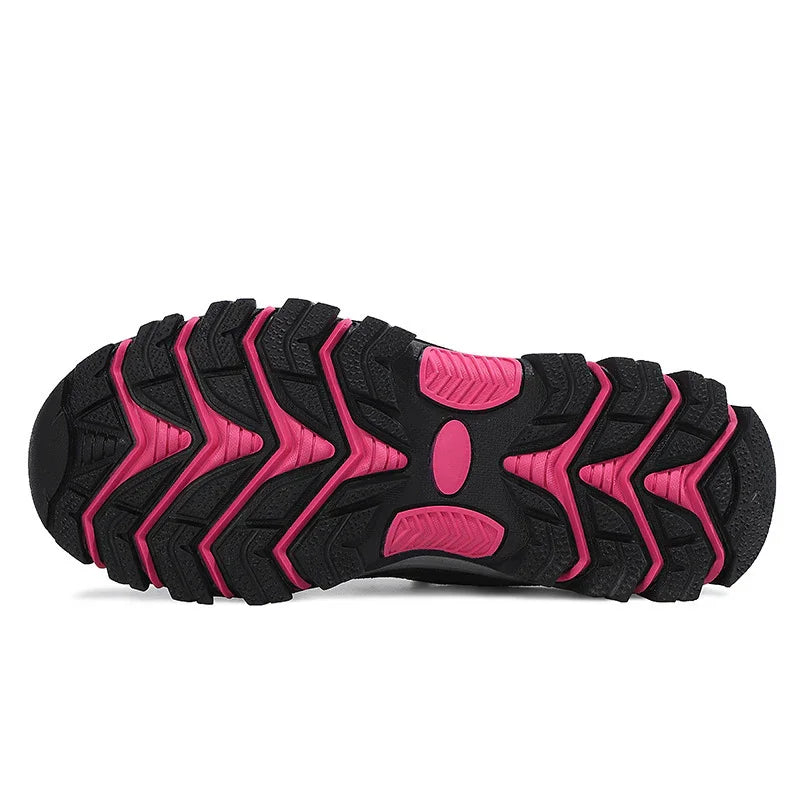 Close-up of black and pink rugged rubber sole of a trail running shoe with deep treads