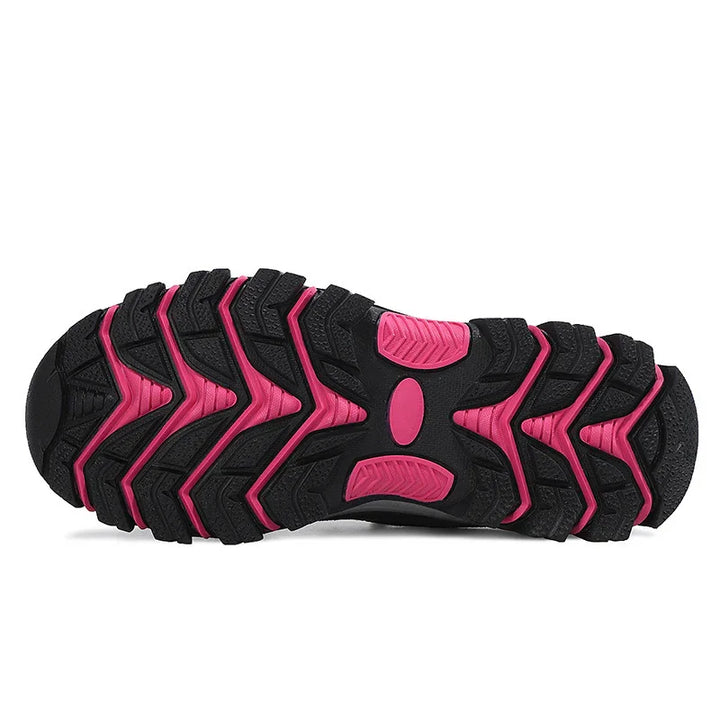 Close-up of black and pink rugged rubber sole of a trail running shoe with deep treads