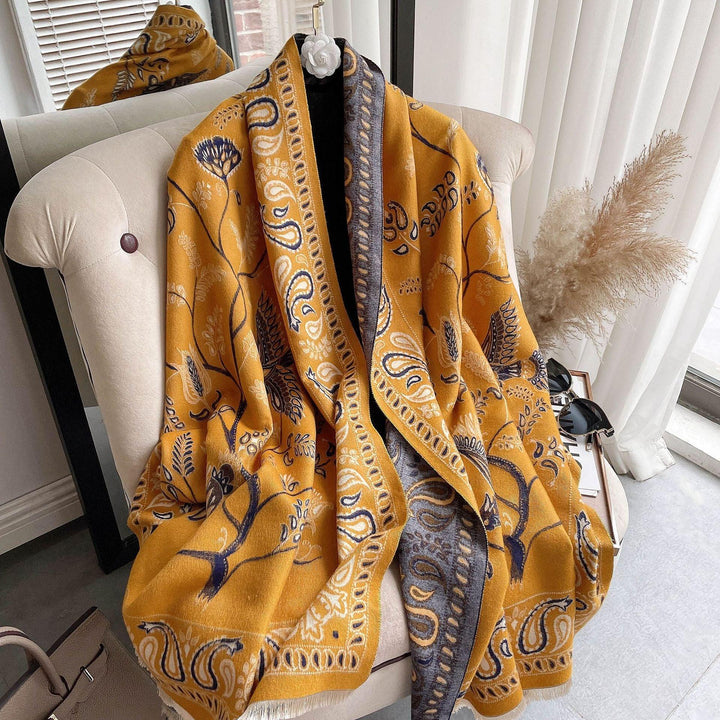 Yellow paisley patterned shawl draped over beige armchair with pampas grass nearby