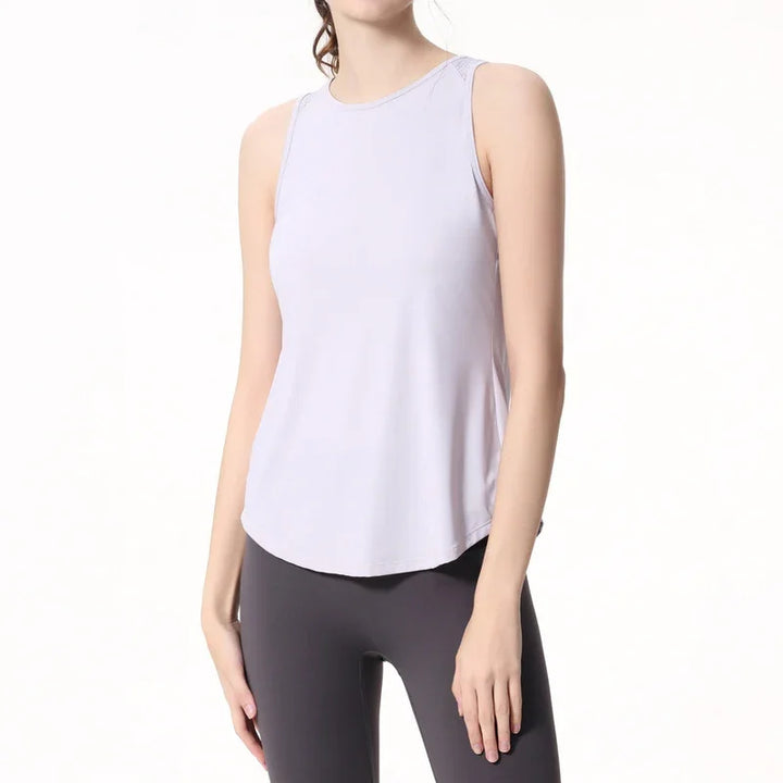 Woman wearing sleeveless white athletic tank top and black leggings on white background