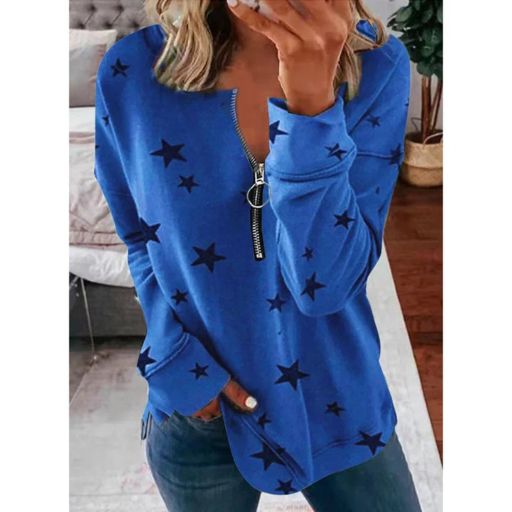 Woman wearing blue star-print zip-up sweatshirt with ring pull zipper in casual indoor setting