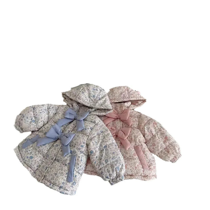 Two floral patterned puffer jackets for toddlers with hoods and large fabric bows in blue and pink