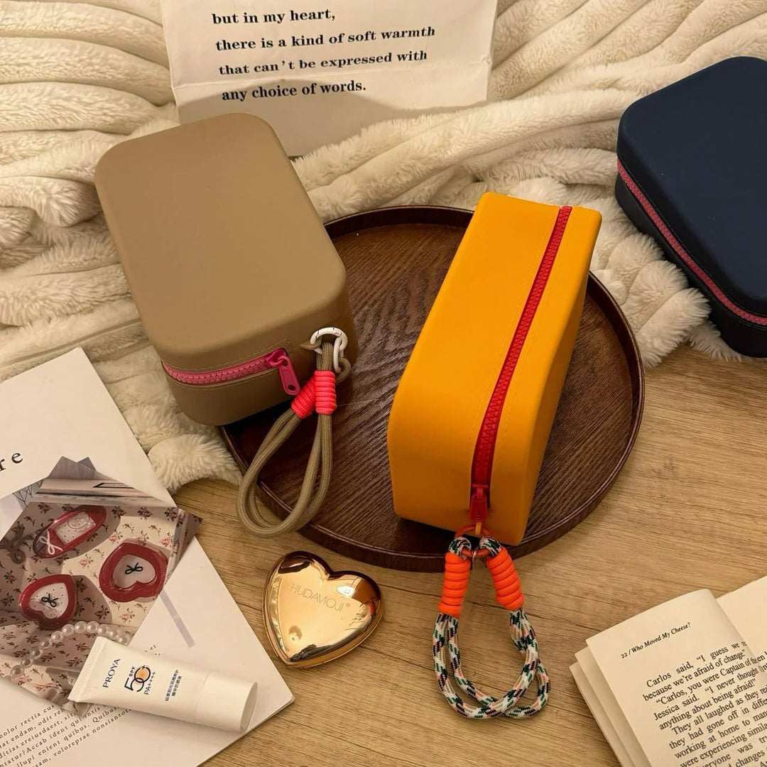 Rectangular colorful pouch bags with zipper and wrist strap on wooden tray and cozy blanket with books
