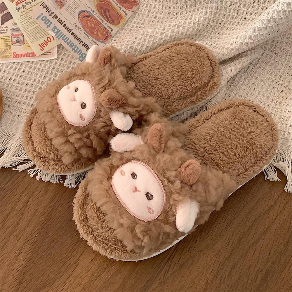 Cozy brown fluffy slippers with cute sheep faces and ears on a wooden floor