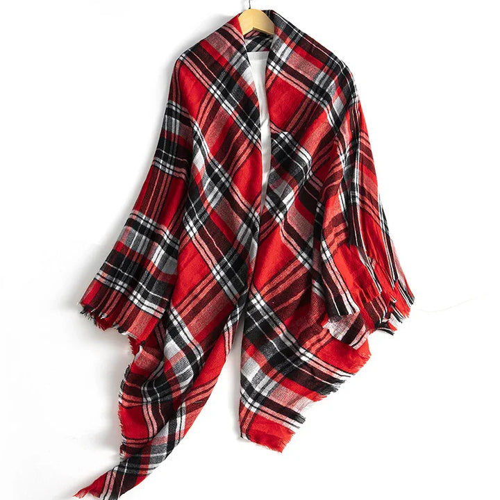 Red black white plaid cozy scarf with fringed edges hanging on wooden hanger