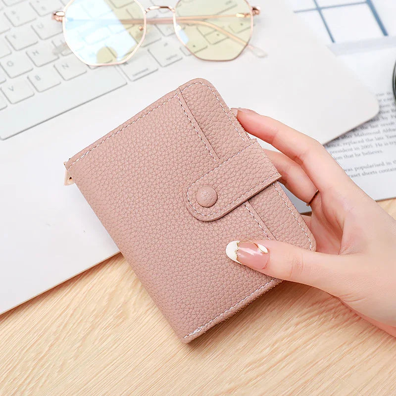 Hand holding textured beige wallet with snap button on wooden desk near keyboard and eyeglasses