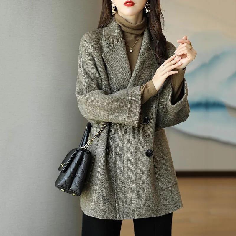 Woman wearing brown herringbone blazer over brown turtleneck with black quilted handbag and gold jewelry