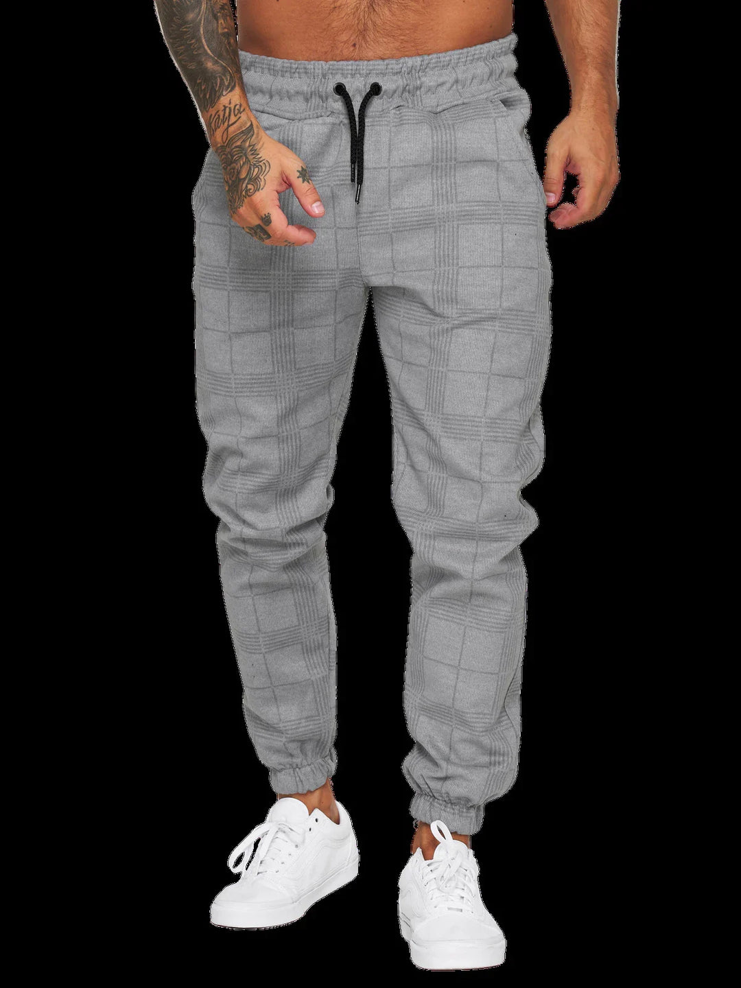 Man wearing light gray plaid jogger pants with black drawstrings and white sneakers