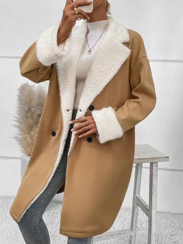 Woman wearing camel coat with white faux fur collar and cuffs over ribbed turtleneck and jeans
