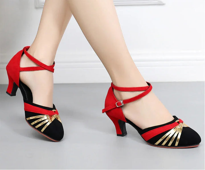 Black and red women's dance shoes with gold accents and low heels on gray floor