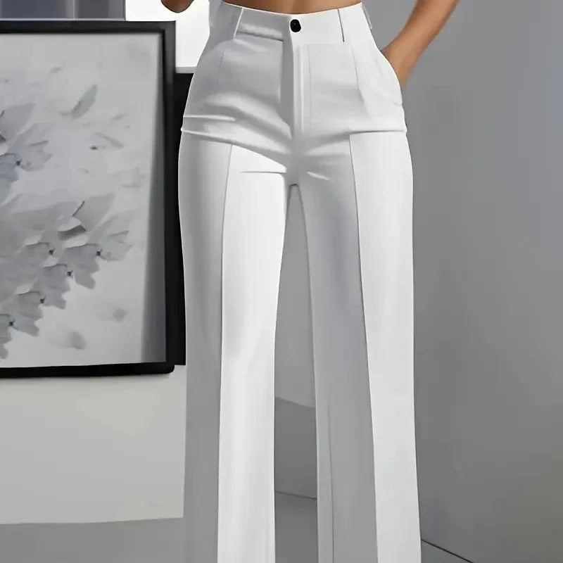 Woman wearing white high-waisted tailored wide-leg pants with a black button in a modern indoor setting