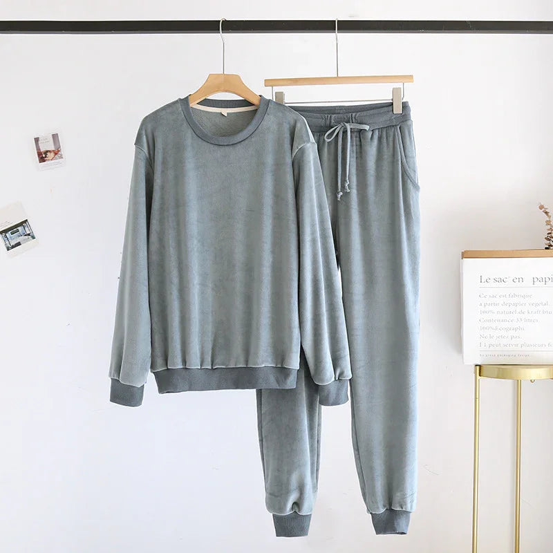 Light blue soft fleece sweatshirt and jogger pants set hanging on wooden hangers against white wall