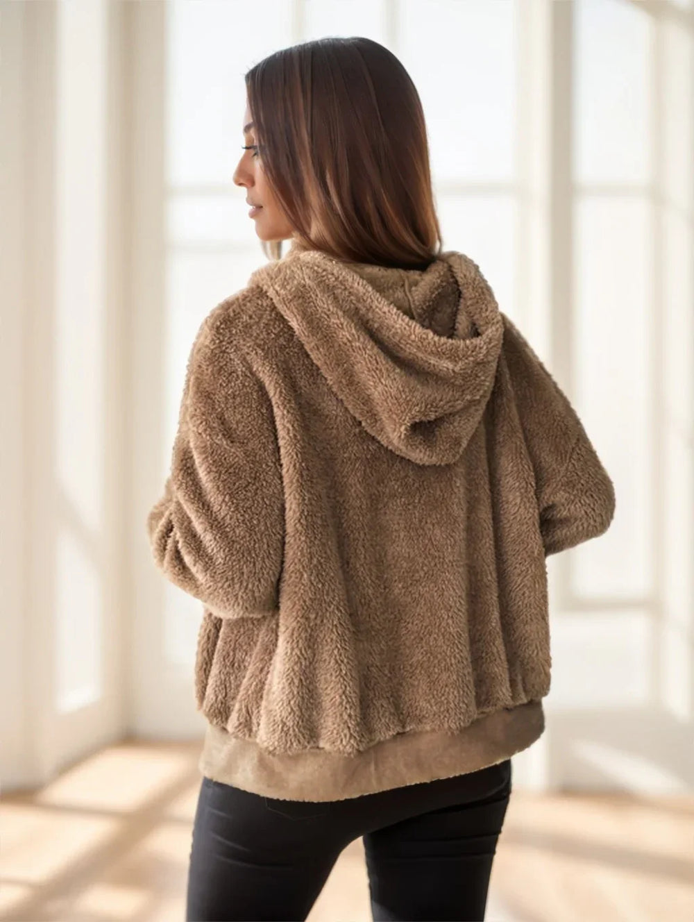 Woman wearing a cozy brown sherpa fleece hooded jacket indoors with natural light
