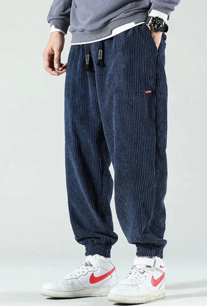 Men's navy blue corduroy jogger pants paired with white and red Nike sneakers