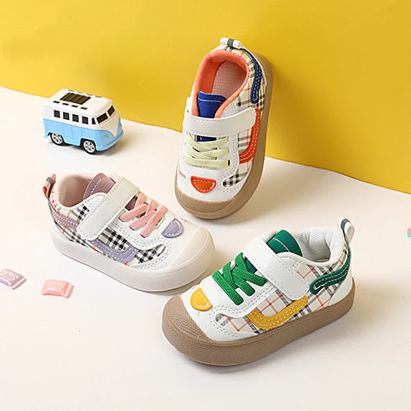 Colorful toddler sneakers with plaid patterns and velcro straps on white surface with yellow background