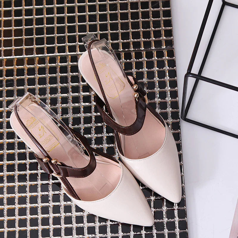 Pair of stylish white pointed toe slingback heels with brown straps on metal grid surface